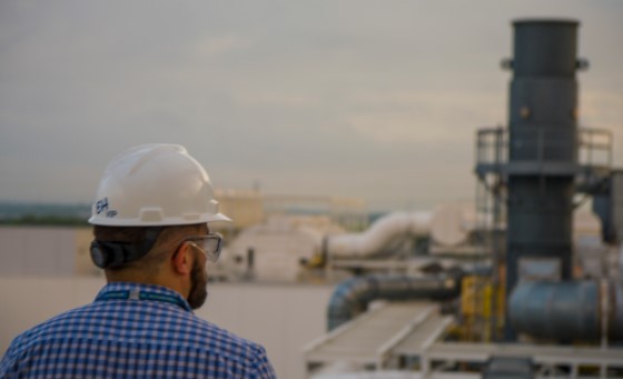 Man in hardhat looks over oil field