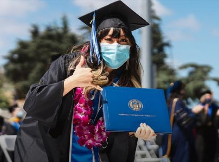 California State University Graduate holding up diploma