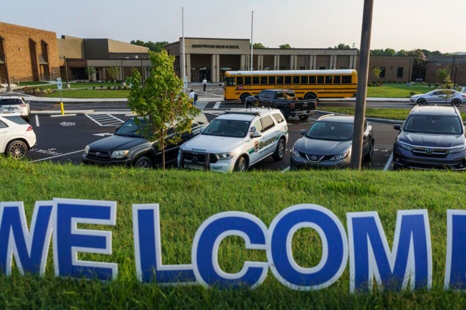 Students make their way into Brentwood High School outside of Nashville as the new school year begins. Welcome sign in forground and a bus and cars in the background.