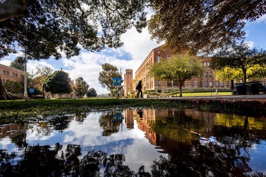 A pedestrian is reflected in puddles of water that has soaked Southern California after historic storms at UCLA in Westwood